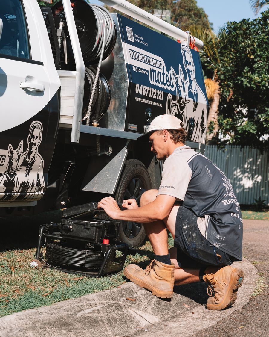 Mason kneeling at the back of the work ute checking equipment